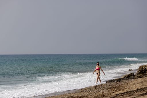 A middle aged woman walking on the beach of the Mediterranean Sea