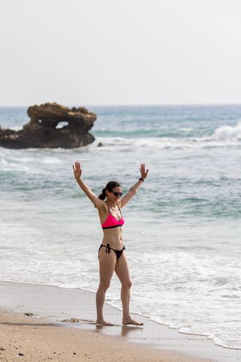 A vertical shot of a middle aged woman walking on the beach of the Mediterranean Sea