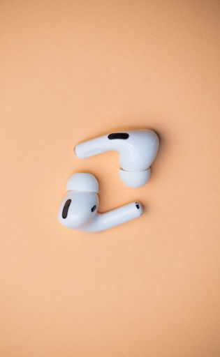 A vertical shot of White Wireless Headphones isolated on orange Background