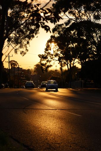 A vertical shot of cars moving on the road during sunset