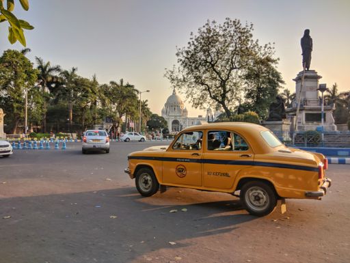A yellow cab on the Queen's Way on the background of the Victoria Memorial Museum