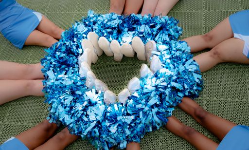 A group of cheerleaders with their feet forming a heart of pompoms