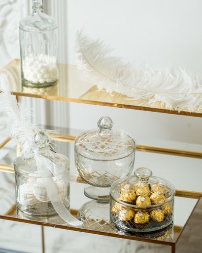 A vertical shot of bottles and containers of chocolate and white feathers on a table