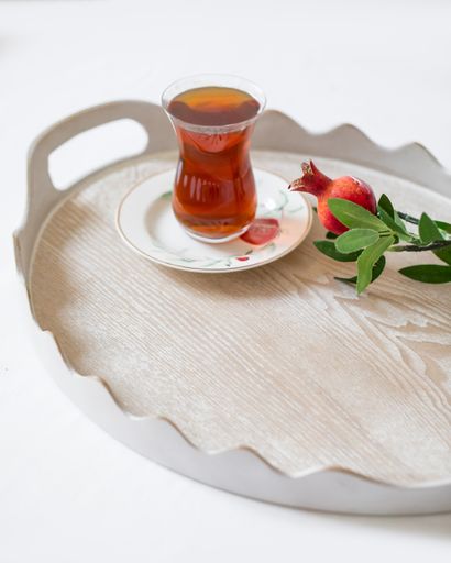 A tray of traditional Turkish cup of tea next to a small pomegranate