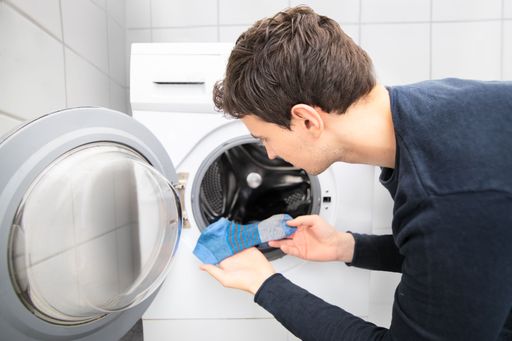 A man looking for a missing sock in a washing machine