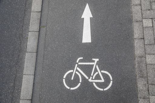 A bicycle lane ahead sign with arrow which shows the direction painted on asphalt street