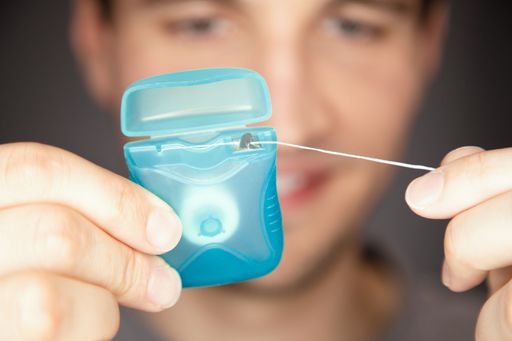 A male pulling floss out of box ready to use and get stucked food out of teeth