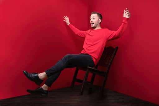 A man in red showing fall from a chair with hands wide open