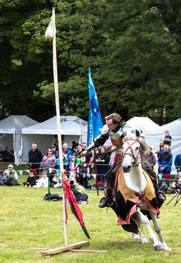A vertical of a knight rider on horse cutting rope to raise a flag at a medieval event in Linlithgow,UK