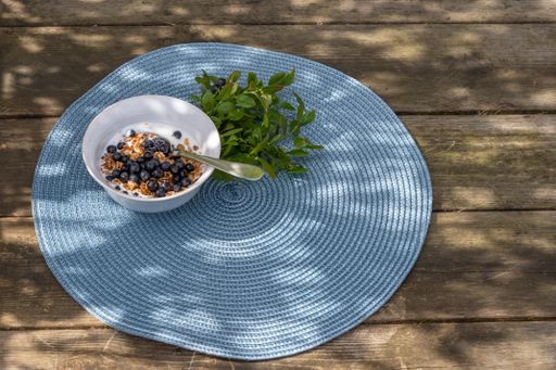 A high angle view of cereal with yogurt and berries in a bowl on a napkin on the table