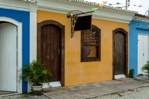 Beautiful facade.Decorated with a potted plant. Old house in orange color with brown wooden doors and window. City of Porto Seguro. Bahia. Brazil.
