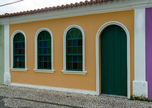 Details in white. Nice facade. City of Porto Seguro. Bahia. Old house in orange color and green door and windows.