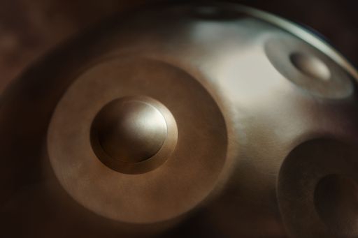 A close-up view of a musical instrument called a handpan, also known as a hang or pantam.