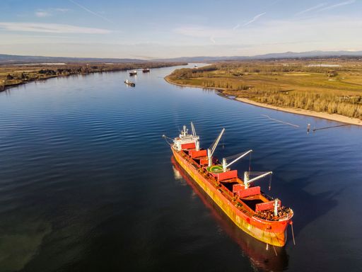 An aerial shot cargo ship floating on the Columbia river near Portland during the daytime under a blue sky