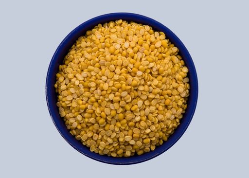 An isolated shot of a blue bowl full of yellow lentils on a white background