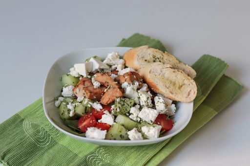 A closeup shot of a bowl of Greek salad with bread slices