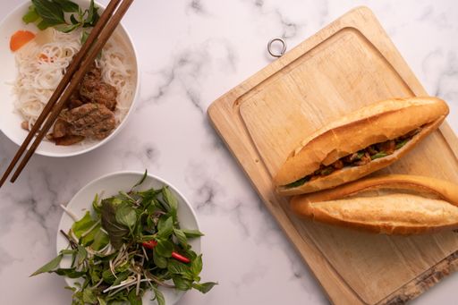 A high angle shot of banh mi, a Vietnamese pork sandwich on a cutting board on a marble surface