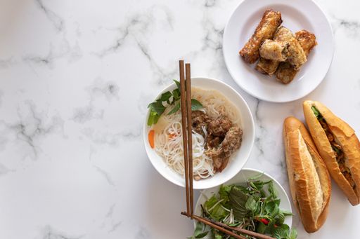 A high angle shot of different Asian dishes with chopsticks on a marble surface