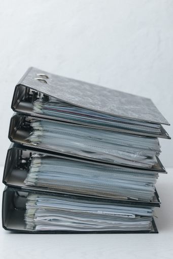 A closeup shot of four black folders with lots of documents piled one on another