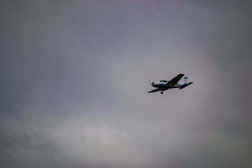 A low-angle shot of an airplane flying in the sky with a cloudy blue sky background