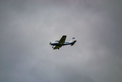 A low-angle shot of an airplane flying in the sky with a cloudy blue sky background