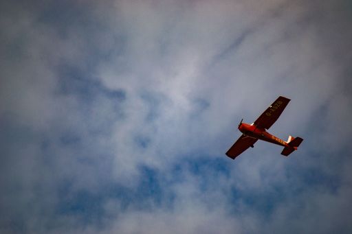 A low-angle shot of an airplane flying in the sky with a cloudy blue sky background