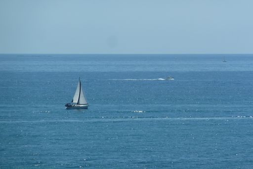 An aerial shot of a sailboat in blue sea under clear sky
