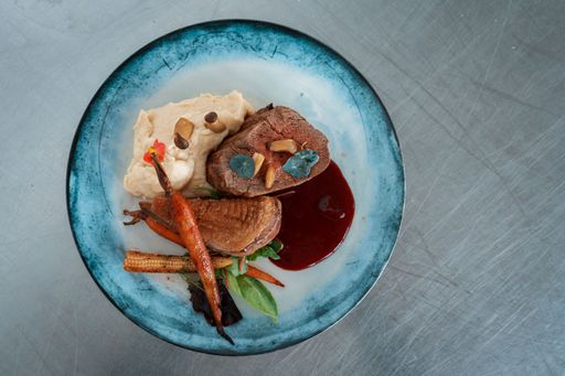 A closeup shot of an appetizing steak with beautiful decorated garnish on a plate