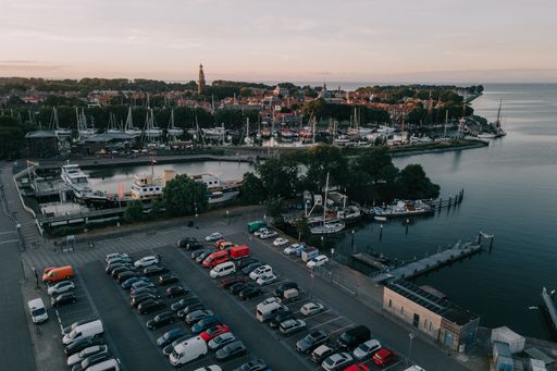 An aerial view of sailing boats moored in the lake and cars parked in Enkhuizen, Netherlands at sunset