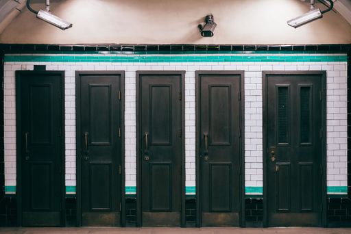 A row of five black wooden doors on the wall from the hall