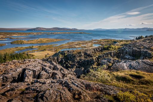 A scenic landscape of big rocky hills with a beautiful lake in the background in Iceland