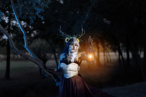 A young girl with deer costume and horns posing for the camera in the forest