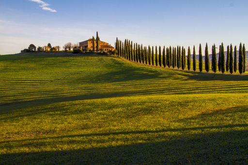 A beautiful shot of a country house in the middle of a field surrounded by hills under the clear sky