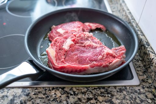 A selective focus shot of meat in a pan on the induction.