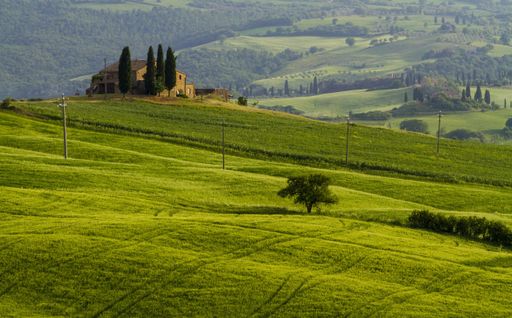 A beautiful shot of a country house in the middle of a field surrounded by hills under the clear sky