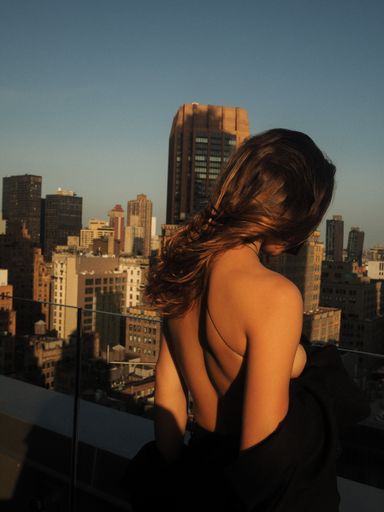 A vertical shot of a female looking out into a city