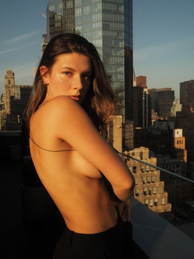 A vertical shot of a female facing the camera with a city in the background