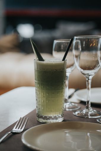 A vertical shot of a green alcoholic cocktail on a bar table