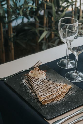 A vertical shot of delicious pancake with chocolate syrup and whipped cream in a restaurant