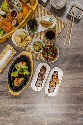 A vertical high angle shot of different Asian dishes on a wooden table