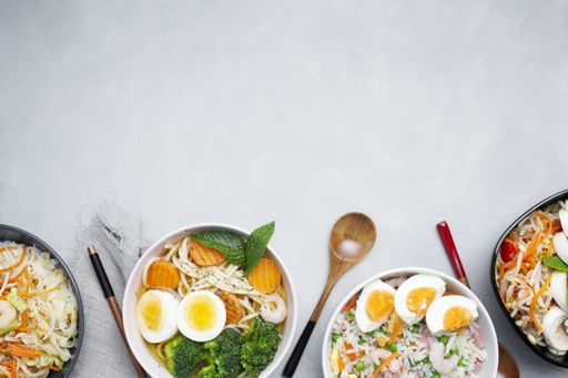 A top view of Asian food made with eggs, vegetables, noodles and other ingredients on a white background with copy space - great for menu use