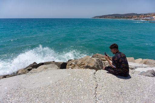A young male taking a photo on the rocks at the beach