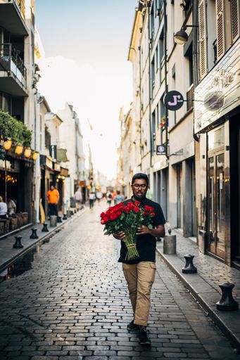 A vertical shot of a man with flowers walking on a paved street in Sevilla, Spain