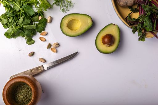 A bowl of freshly chopped assorted vegetables and avocados atop a white surface