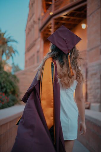 A vertical shot of a Caucasian female seen from behind, with a graduation gown