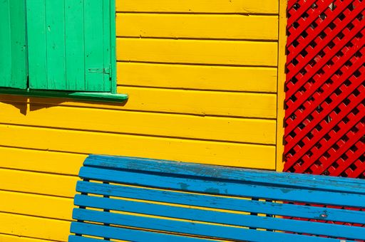 A blue wooden bench in front of a colorful house's outer wall in La Boca, Buenos Aires, Argentina