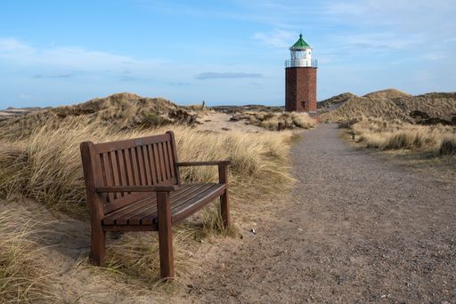 The Kampen lighthouse and a wooden bench against the blue sky in Sylt, North Frisia, Germany