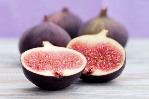 A selective focus shot of fresh figs cut in half on a wooden surface