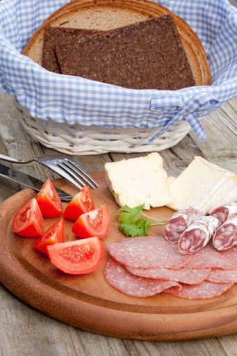 A vertical shot of cheese, tomatoes, bread and smoked sausages