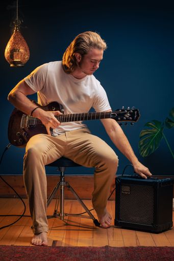 A vertical shot of a young caucasian man playing an electric guitar